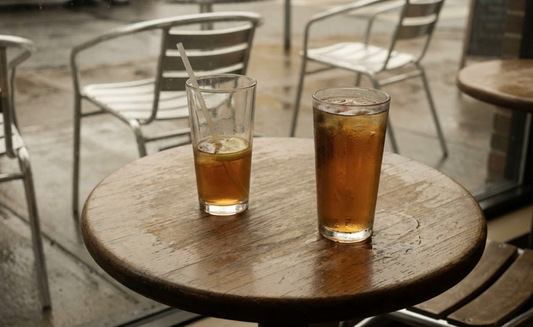Two glasses of iced tea on a café table one untouched with condensation representing grief after losing a friend
