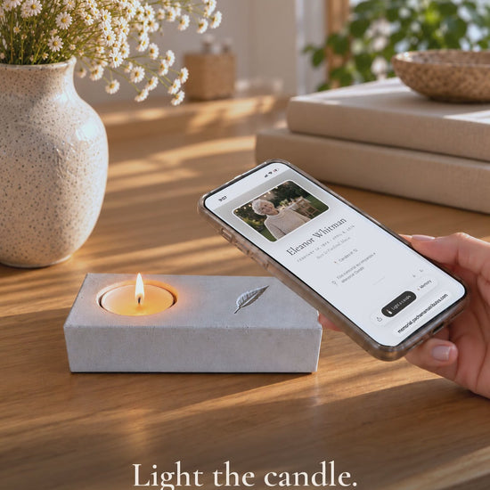 Video: a tea light is lit in the handmade concrete memorial candle holder, a phone rests on the engraved feather and the online memorial opens.